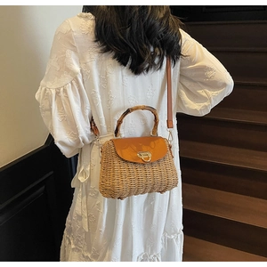 Detailed view of woven straw bag with bamboo handle and leather strap on staircase