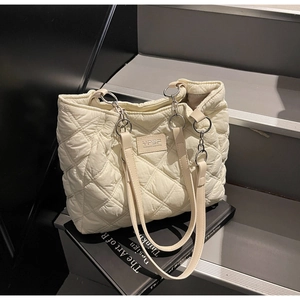 Detail der cremefarbenen Stepptasche mit Rautenmuster und Kettentragegurt aus Metall