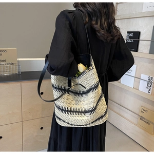 Détail d'un sac cabas tissé avec rayures noires et blanches et fine bandoulière en cuir