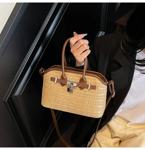 Detail of hand-woven straw crossbody bag with leather trim and silver padlock closure
