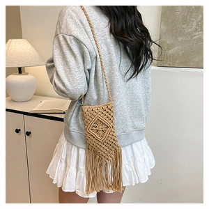 Fashionable woven straw cell phone bag with tassels shown on model for summer holiday vibe