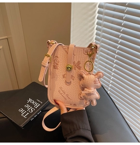 Detailed macro view of pink litchi leather mini crossbody bag with cute bear charm