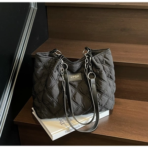 Detail der schwarzen Stepptasche mit Rautenmuster und Leder-Ketten-Schultergurt