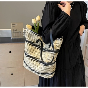 Détail d'un sac cabas tissé à rayures avec anses en cuir noir dans un intérieur