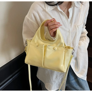 Detail of lemon yellow patent leather tote bag with dual front pockets and shoulder strap