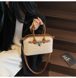 Close-up of woven straw handbag with brown leather trim and metallic padlock detail