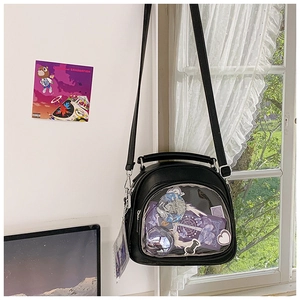 Detail of black ita bag with semi-circular clear window displaying anime badges
