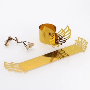 Close-up of golden glitter laser cut angel wing napkin rings for wedding decor
