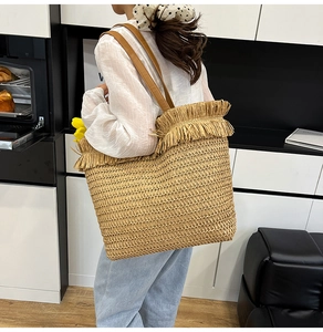 Close-up of woven straw tote bag featuring detailed fringe edges and leather straps