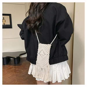 Chic cream woven crossbody bag with long tassels and geometric texture worn by a model