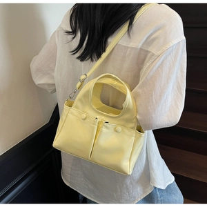 Close-up of yellow patent leather tote bag with double pockets and cutout handle