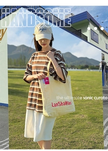 Détail d'un grand sac cabas en toile blanc avec logo rouge et t-shirt rayé