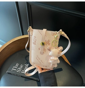 Close-up of pink litchi grain leather crossbody bag with cartoon teddy bear pattern