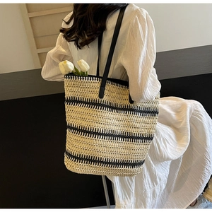 Détail du cabas tissé à rayures beiges et noires avec de longues bretelles en cuir noir