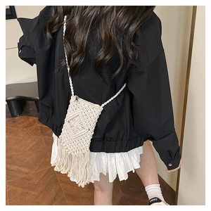 Model view of cream woven straw crossbody bag with handmade tassel details for beach