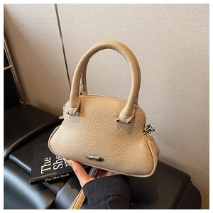 Detailed macro shot of beige pebble leather handbag with silver hardware and handle