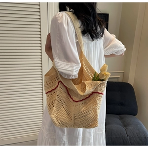 Detail of hand-woven off-white crochet tote bag with red stripes worn on shoulder