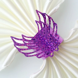 Close-up of sparkling purple butterfly napkin ring with hollow-out design on white napkin