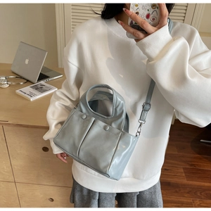Lifestyle shot of woman wearing the blue PU leather tote bag with silver hardware