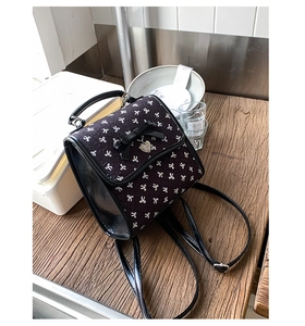 Nahaufnahme des schwarzen Mini-Rucksacks mit weißen Schleifen und Herz-Metallanhänger