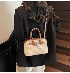 Close-up of woven straw handbag with brown leather straps and silver metal buckle