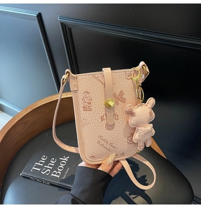 Close-up of pink crossbody bag with bear print and leather texture on a wooden chair