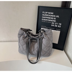 Detailansicht der grauen Stepptasche mit silbernem Metallring und Leder-Logo-Etikett