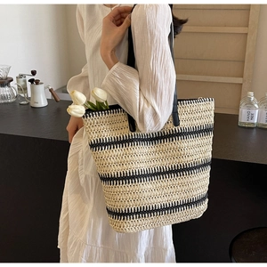 Gros plan détaillé du sac cabas tissé à rayures noires et anses en cuir dans un café