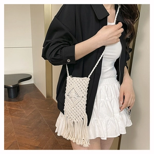 Detail of hand-woven straw crossbody bag with tassels and geometric patterns for beach style