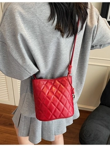 Elegante borsa a secchiello trapuntata rossa con tracolla in pelle per donna in interno chic