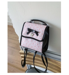 Detailansicht des rosa geprägten Mini-Rucksacks mit schwarzer Lederschleife und Herz-Anhänger