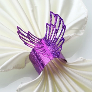 Macro detail of purple glitter laser-cut butterfly napkin ring on a white satin cloth