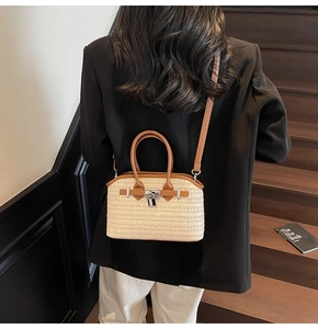Detail of hand-woven straw crossbody bag with brown leather trim and metal lock closure