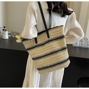 Détail du sac cabas en paille tissée avec rayures noires et texture de poignée en cuir
