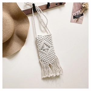 Detailed macro view of cream woven cotton fringe bag with intricate bohemian patterns
