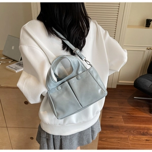 Detail view of light blue PU leather tote bag with dual front pockets on a model