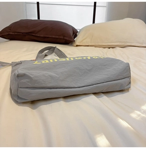 Détail du sac fourre-tout gris en nylon résistant à l'eau avec texte jaune sur le côté