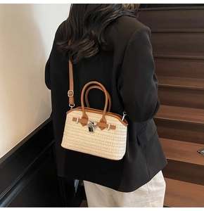 Detailed view of woven straw handbag with brown leather trim worn by a model in a suit