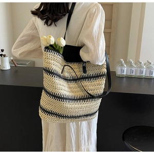 Détail d'un grand sac cabas en paille tissé avec rayures noires porté par un mannequin