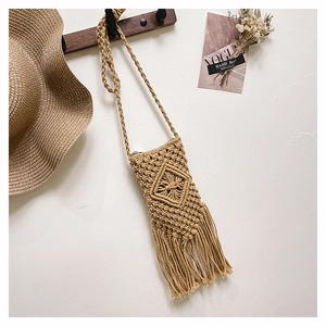 Detailed view of bohemian straw bag featuring tassels and diamond woven texture