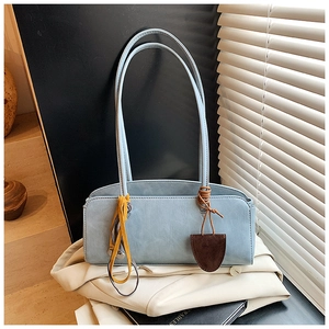 Détail du sac baguette bleu clair avec lanière jaune et breloque marron pendante