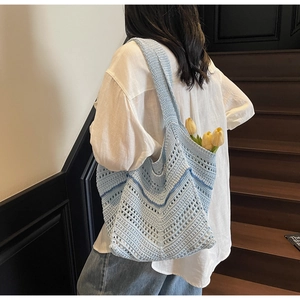 Detail shot of hand-woven light blue hollow tote bag styled with yellow tulips on stairs