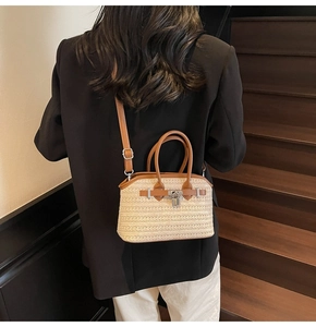 Back view of a model carrying a beige woven handbag with brown leather trim on stairs