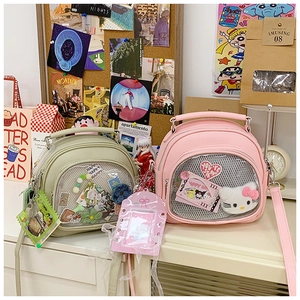 Detail of pink and green ita bags with transparent windows for pins and plush toys