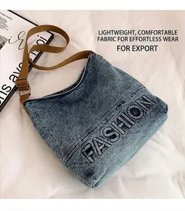 Detail of blue denim tote bag with FASHION lettering and adjustable brown shoulder strap