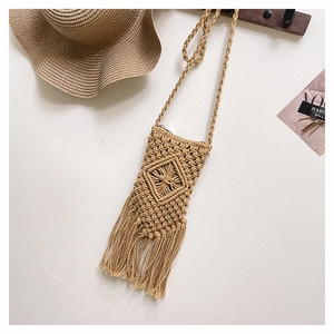 Detail of bohemian woven straw phone bag with tassel trim and diamond knot texture