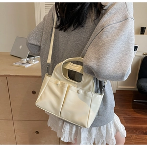 Detail of cream faux leather tote bag showing adjustable shoulder strap and metal hardware