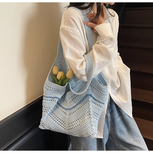 Close-up of light blue hand-woven hollow tote bag with stylish wavy crochet pattern detail