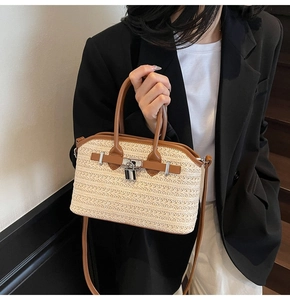 Detail of woven straw handbag featuring brown leather trim and silver metal buckle