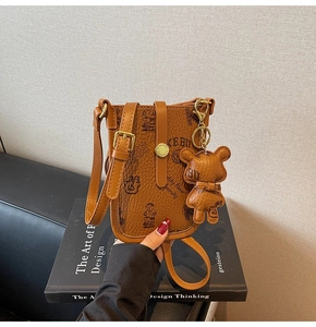Detailed view of brown litchi grain leather phone bag with vintage teddy bear print